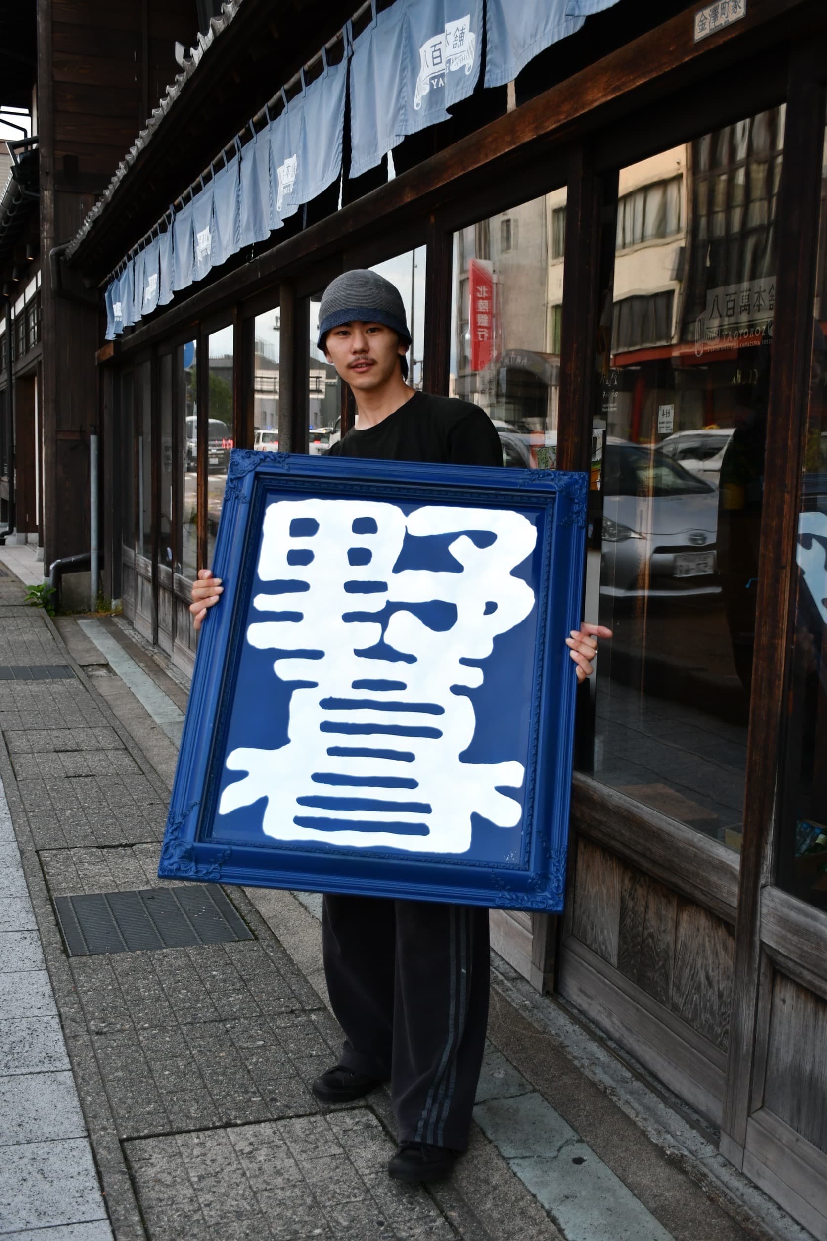 野暮の看板を持つ栗原稜